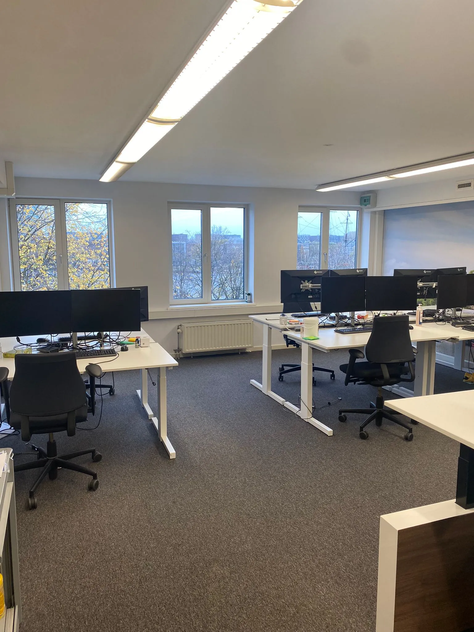 Modern kantoor met verstelbare bureaus en meerdere computerschermen aan de Prins Hendrikkade.